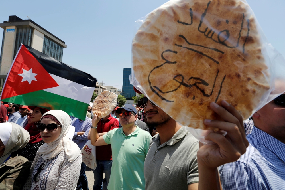 FILE PHOTO: Protesters chant slogans as they hold bread in front of the Labour Union offices in Amman, Jordan, June 6, 2018. REUTERS/Muhammad Hamed