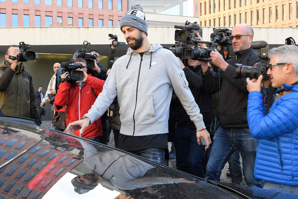 Journalists gather around Barcelona's Spanish defender Gerard Pique (C) as he leaves after appearing in court for driving without a valid licence in Barcelona on November 26, 2018. / AFP / LLUIS GENE
