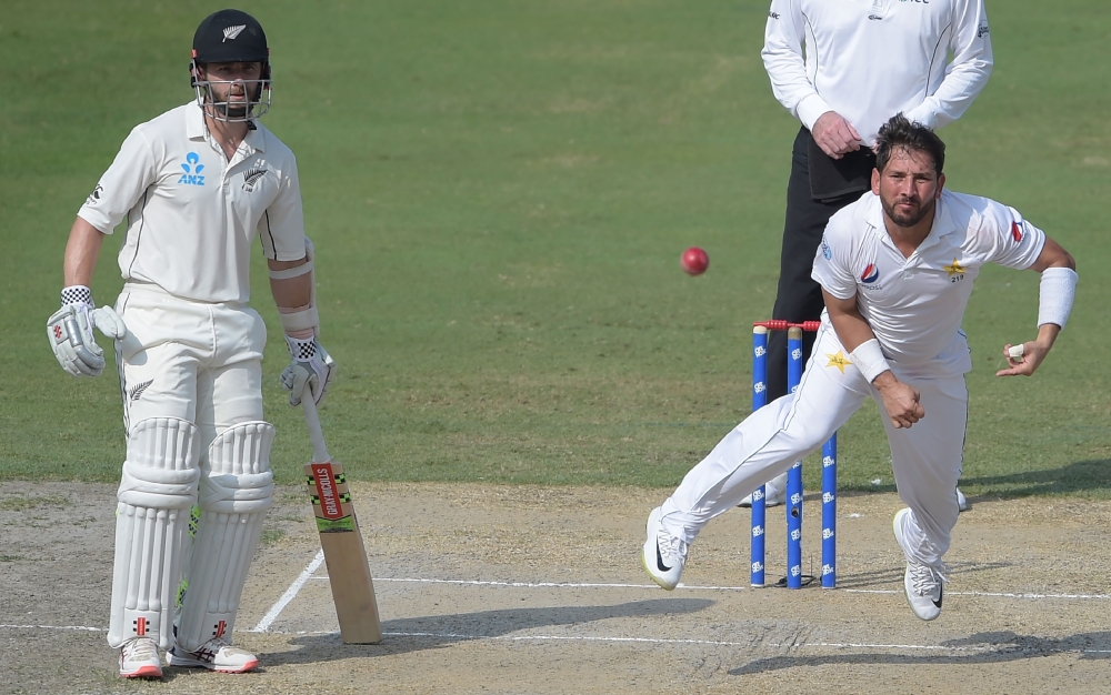 Pakistani spinner Yasir Shah (R) delivers the ball as New Zealand captain Kane Williamson (L) looks on during the third day of the second Test cricket match between Pakistan and New Zealand at the Dubai International Stadium in Dubai on November 26, 2018.