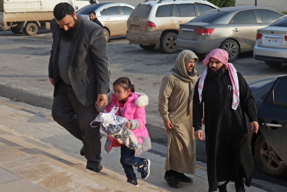 Members of the civilian branch of the powerful Hayat Tahrir al-Sham (HTS) alliance, which is led by the jihadists of Syria's former Al-Qaeda affiliate, escort four-year-old girl named Yasmine near the Bab al-Hawa crossing with Turkey on November 26, 2018.