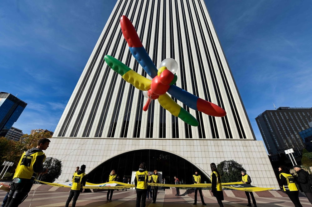 Amnesty International activists hold a giant dragonfly-shaped balloon with a banner reading 