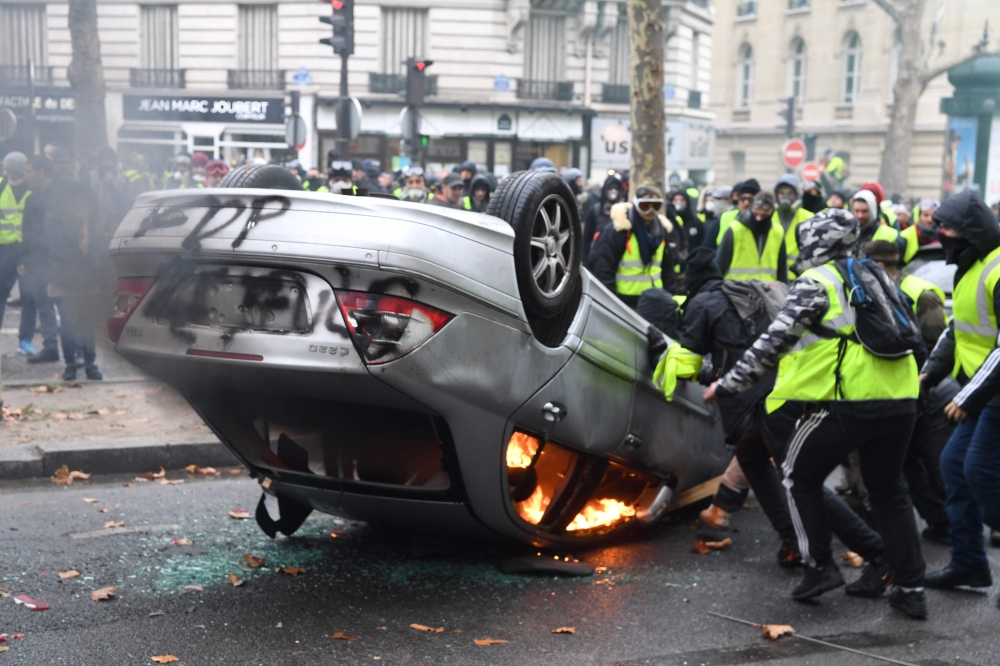 Demonstrators destroy a car during a protest of Yellow vests (Gilets jaunes) against rising oil prices and living costs on the Champs Elysees, in Paris, on December 1, 2018. T  AFP / Alain JOCARD
