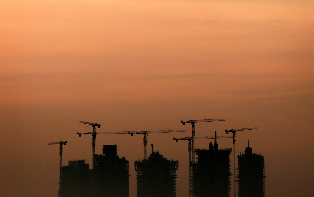 Cranes stand above an apartment complex under construction (Reuters/Tim Wimborne) 