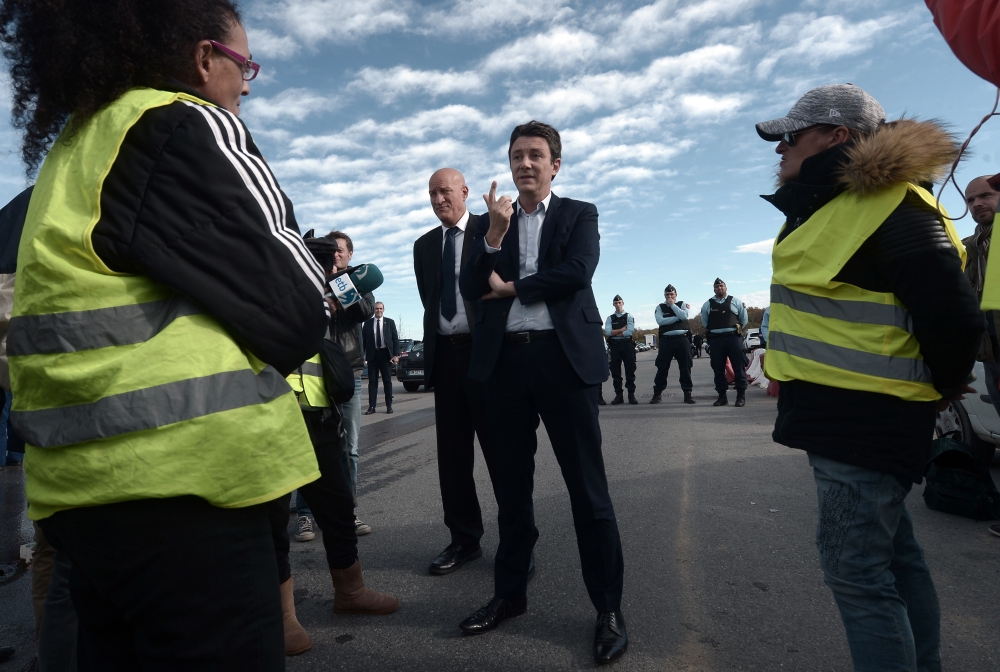 French Government's spokesperson Benjamin Griveaux (C) speaks with yellow vests (gilets jaunes) protestors before an official visit of Copelectronic, a company specialised in electronic and electric components, in Mouguerre, southwestern France, on Novemb