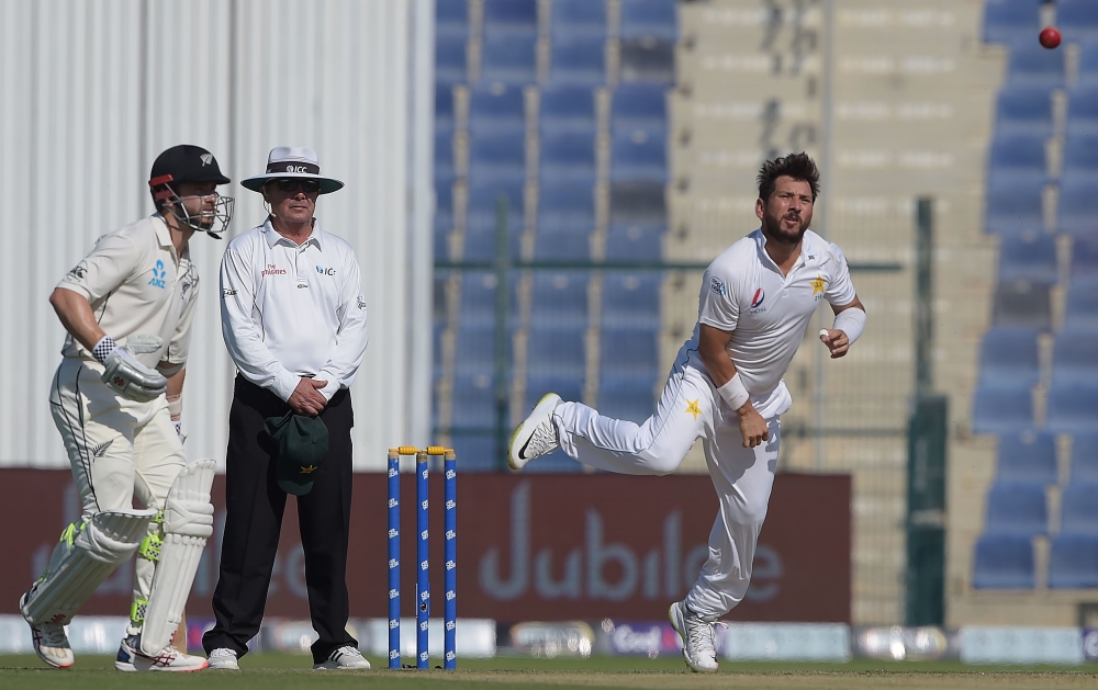 Pakistani spinner Yasir Shah (R) delivers the ball as New Zealand captain and batsman Kane Williamson (L) looks on during the first day of the third and final Test match between Pakistan and New Zealand at the Sheikh Zayed International Cricket Stadium in