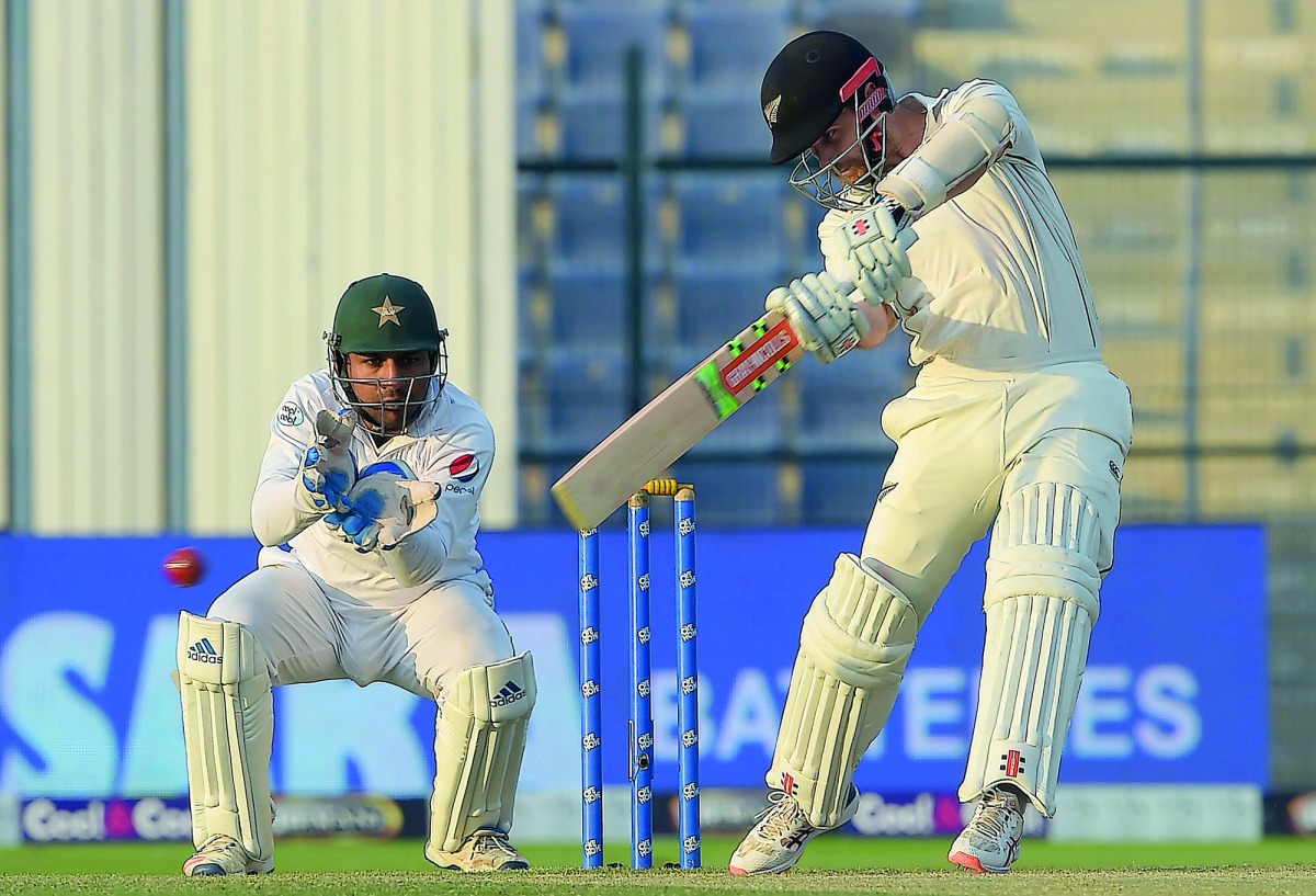 New Zealand captain Kane Williamson (R) plays a shot as Pakistani wicketkeeper captain Sarfraz Ahmed looks on during the third day of the third and final Test cricket match between Pakistan and New Zealand at the Sheikh Zayed International Cricket Stadium