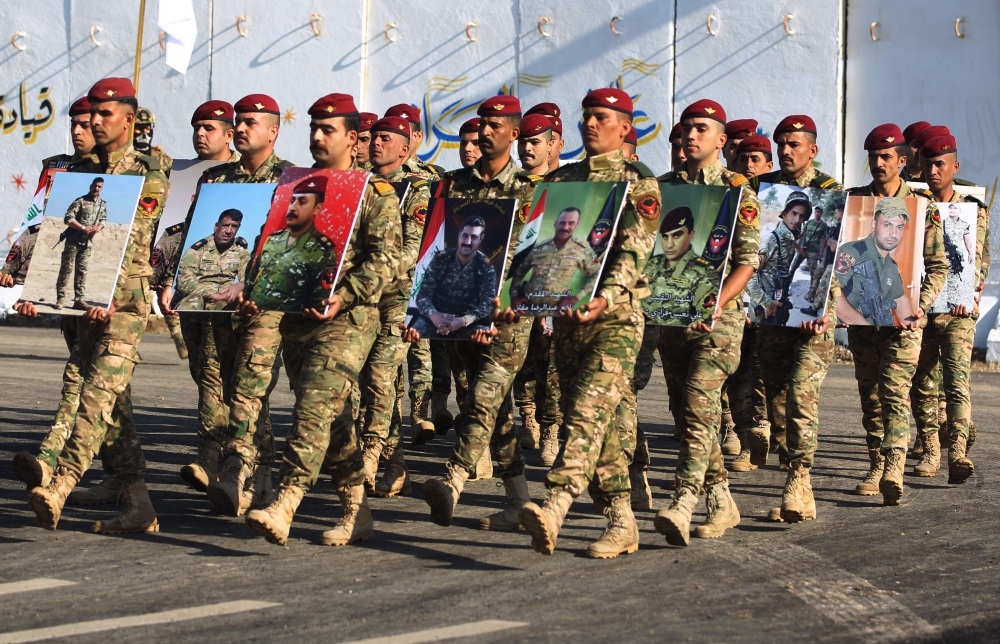 Members of Iraq's Rapid Response military unit hold portraits of fallen soldiers during the fight against Islamic State (IS) group during a ceremony at a military base inside Baghdad's International Airport, to mark the first anniversary of the country's 
