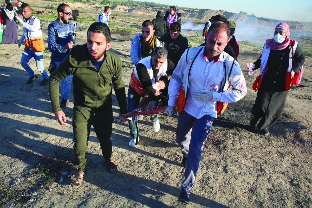 Health team members carry an injured Palestinian during Israeli intervention on the protest within the “Great March of Return” demonstrations at Al Bureij Refugee Camp in Gaza City, Gaza, yesterday.