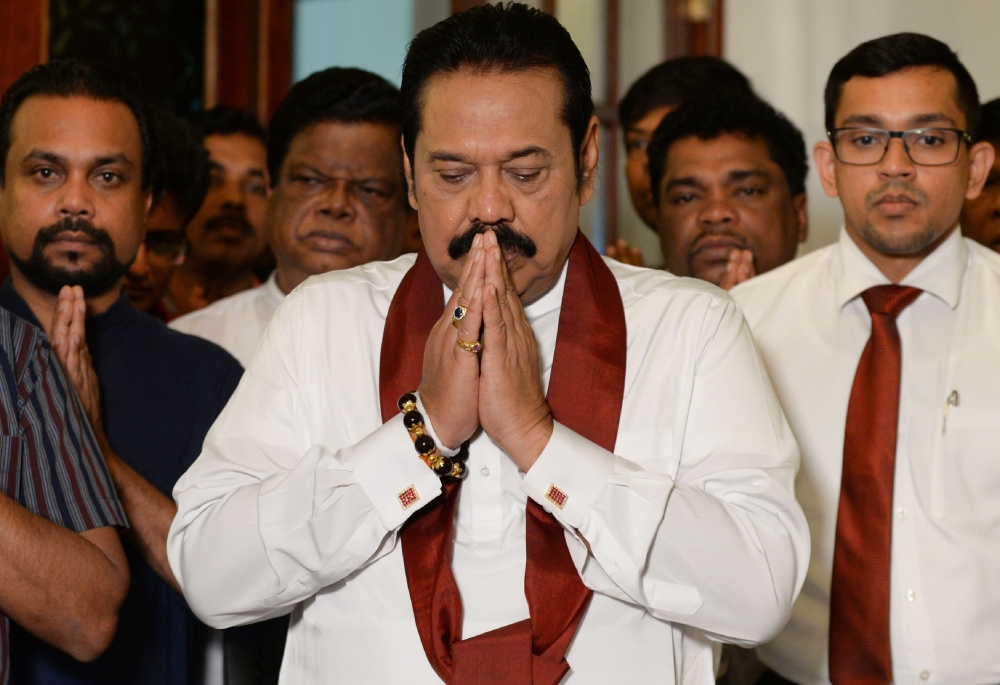Sri Lanka’s former president Mahinda Rajapakse gestures during a ceremony before signing a document backing down from his controversial appointment as prime minister in Colombo on December 15, 2018.  AFP / LAKRUWAN WANNIARACHCHI