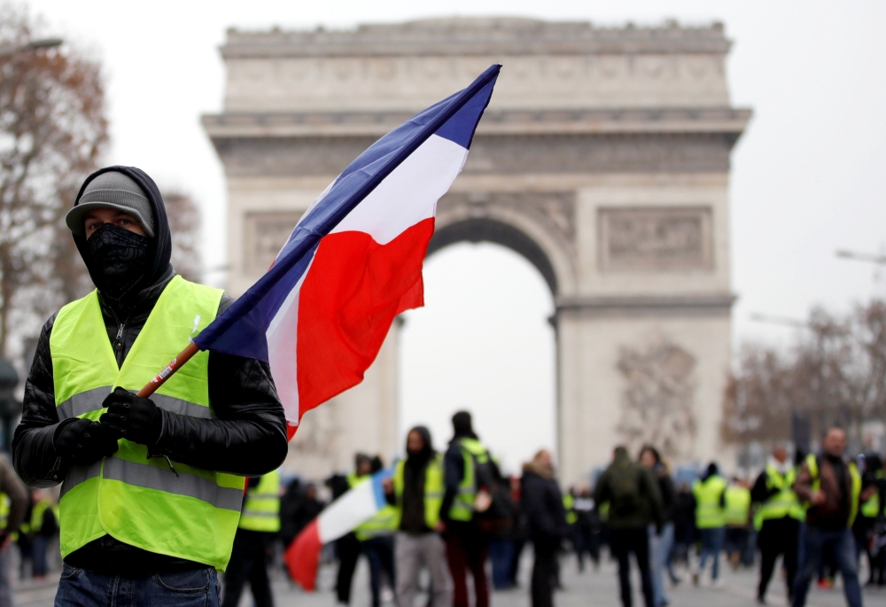 A protester wearing a yellow vest holds a French flag during a demonstration by the 