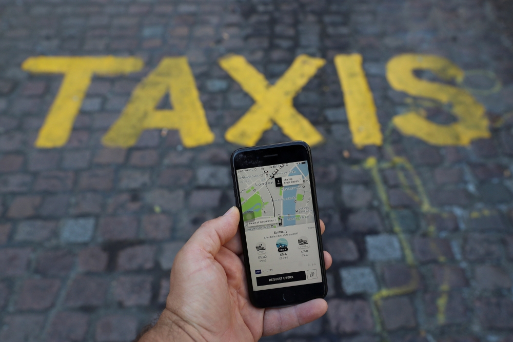 FILE PHOTO: A photo illustration shows the Uber app and a taxi sign in London, Britain, June 26, 2018. REUTERS/Simon Dawson
