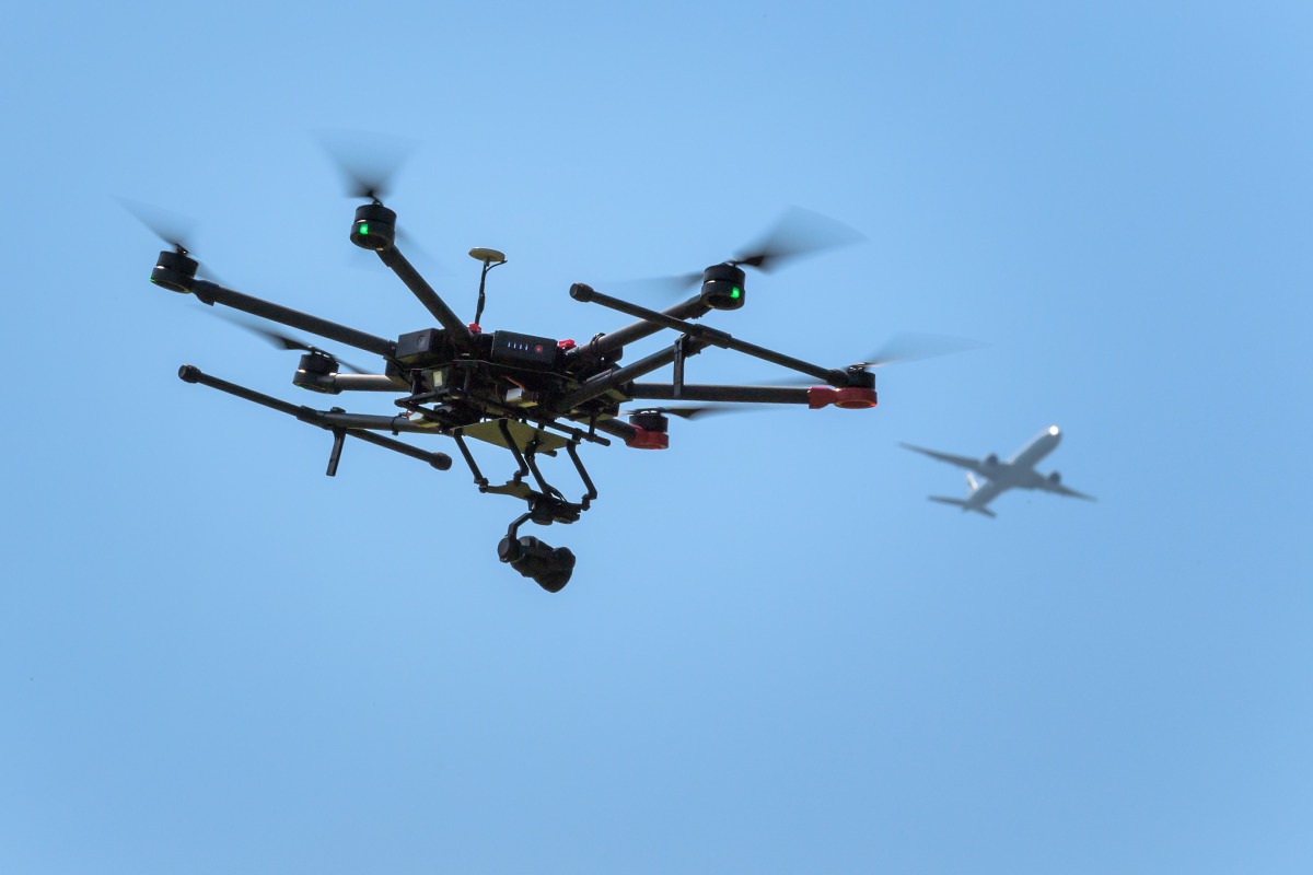 A drone flies as an airplane is seen in the background during a press presentation near Zurich on August 23, 2017. AFP/Fabrice Coffrini