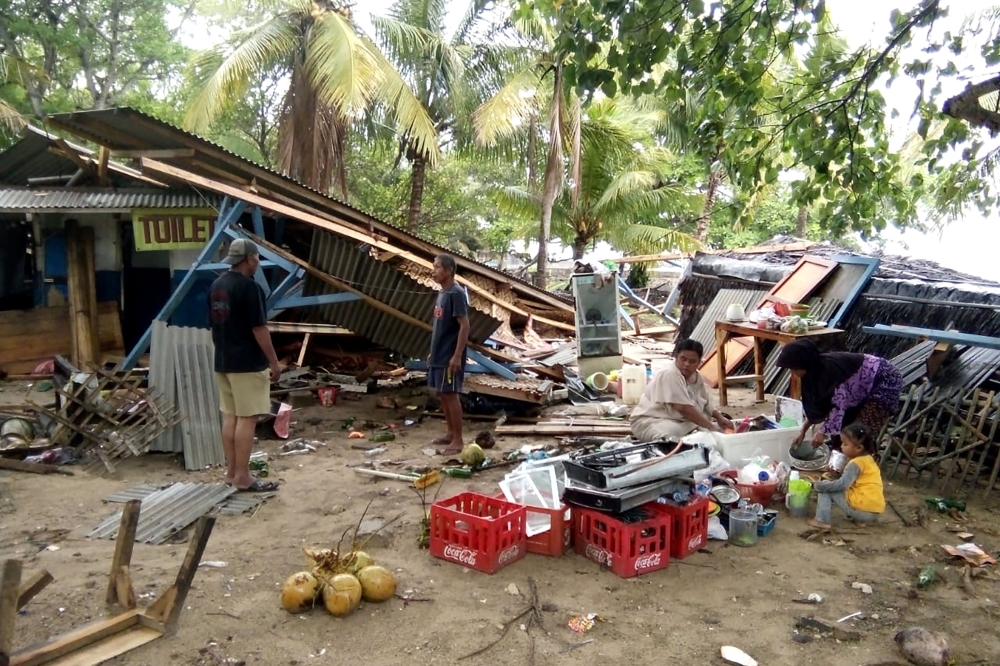 People gather salvageable items from damaged buildings on Carita beach on December 23, 2018, after the area was hit by a tsunami that may have been caused by the Anak Krakatoa volcano. AFP / Semi
