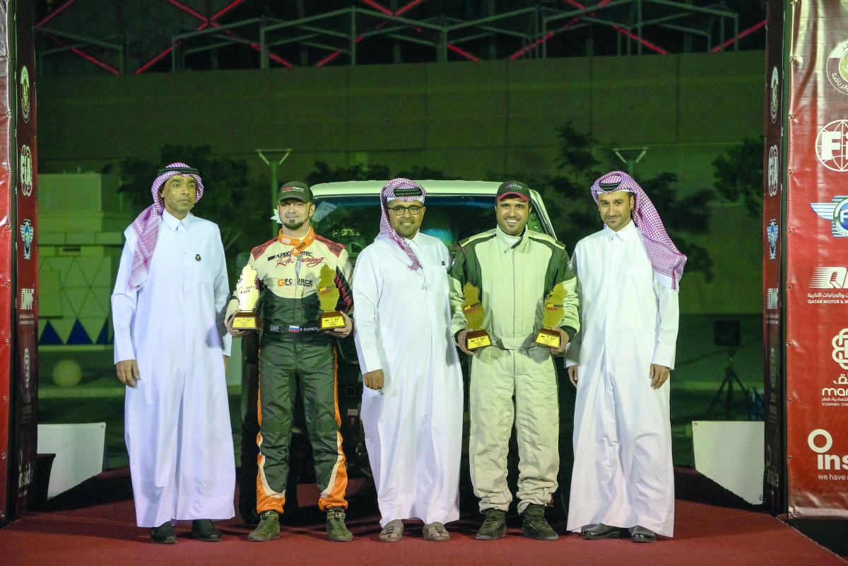 Qatari driver Mohamed Al Meer (fourth left) and his Russian co-driver Alexey Kuzmich celebrate with the  President of Qatar Motor and Motorcycle Federation (QMMF),  Abdulrahman Al Mannai (centre) and General Secretary Abdul Razzaq Al Kuwari (right) after 