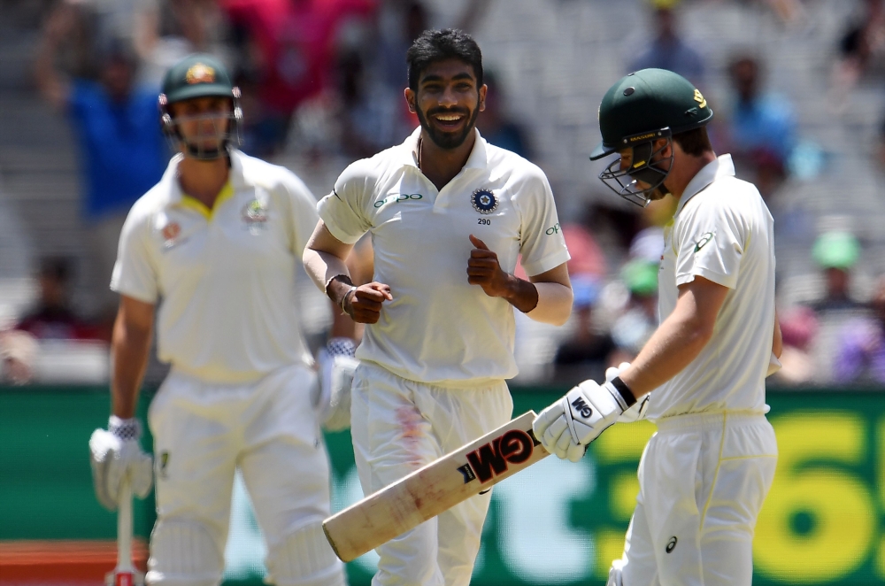 Australia's batsman Travis Head (R) walks off the field as India's paceman Jasprit Bumrah (C) celebrates his dismissal during day three of the third cricket Test match between Australia and India in Melbourne on December 28, 2018. AFP / WILLIAM WEST / -- 