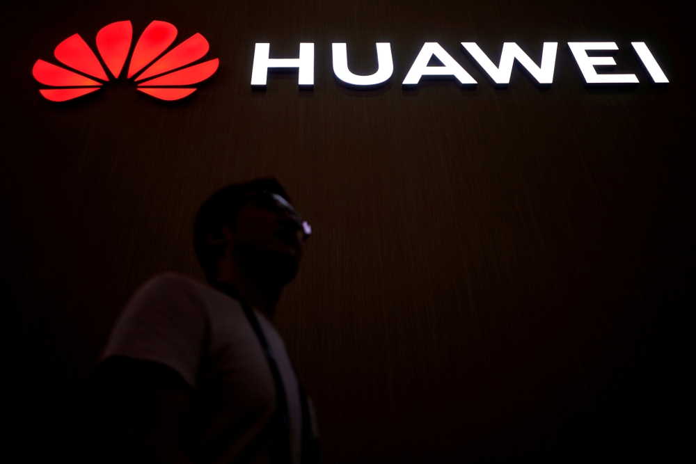 FILE PHOTO: A man walks past a sign board of Huawei at CES (Consumer Electronics Show) Asia 2018 in Shanghai, China June 14, 2018. REUTERS/Aly Song/File Photo/File Photo