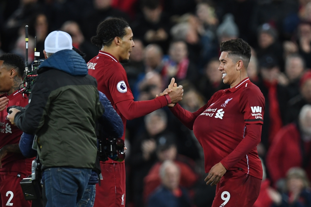 Liverpool's Brazilian midfielder Roberto Firmino (R) takes the match ball and puts it under his sirt following the English Premier League football match between Liverpool and Arsenal at Anfield in Liverpool, north west England on December 29, 2018. AFP / 
