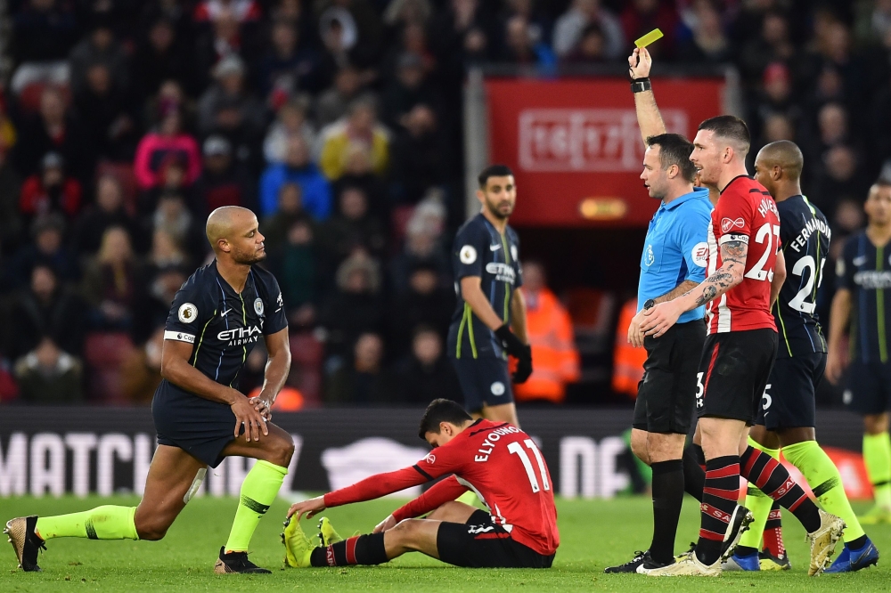 English referee Paul Tierney shows a yellow card to Manchester City's Belgian defender Vincent Kompany (L) during the English Premier League football match between Southampton and Manchester City at St Mary's Stadium in Southampton, southern England on De
