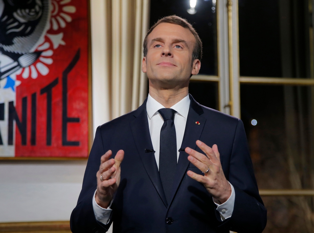 French President Emmanuel Macron gestures as he delivers his New Year wishes during a televised address to the nation from the Elysee Palace in Paris on December 31, 2018. / AFP / POOL / Michel Euler