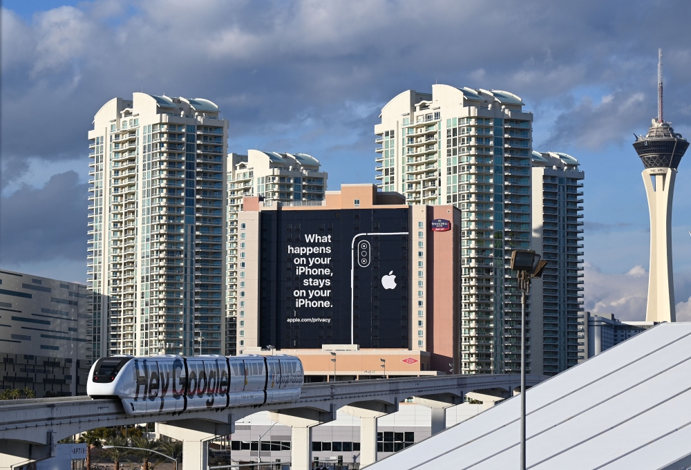 A monorail train plastered with a Google advertisement passes a giant sign from Apple on a building as preparations are underway for the CES 2019 show, January 6, 2018 in Las Vegas, Nevada. AFP / Robyn Beck