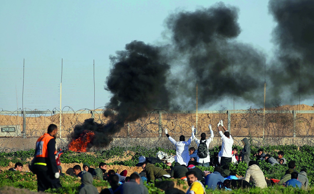 Palestinian medics raise up their hands as they try to evacuate a wounded demonstrator during protest at the Israel-Gaza border fence, in the southern Gaza Strip, yesterday.