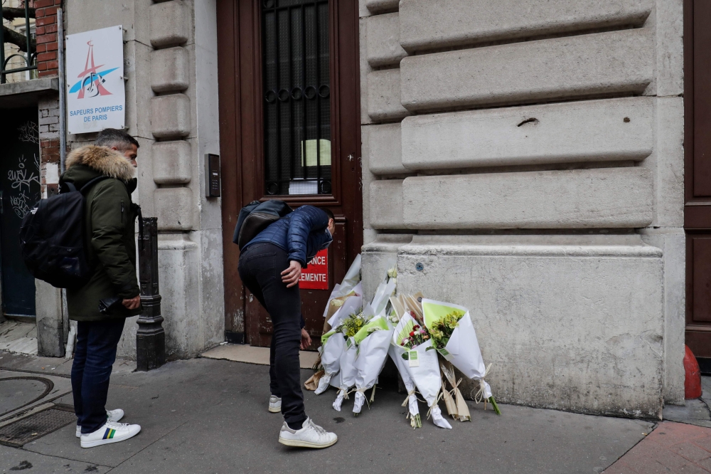 A man lays flowers outside the Paris Fire station in the 9th arrondissement of Paris, in tribute to the two firefighters killed the day before in a powerful gas explosion which tore through a building in central Paris on January 13, 2019.  AFP / Thomas SA