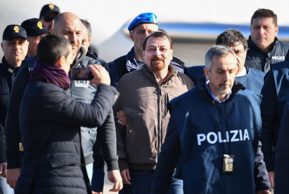 Italian former communist militant Cesare Battisti (C), wanted in Rome for four murders attributed to a far-left group in the 1970s, is escorted by Italian Police officers after stepping off a plane coming from Bolivia and chartered by Italian authorities,