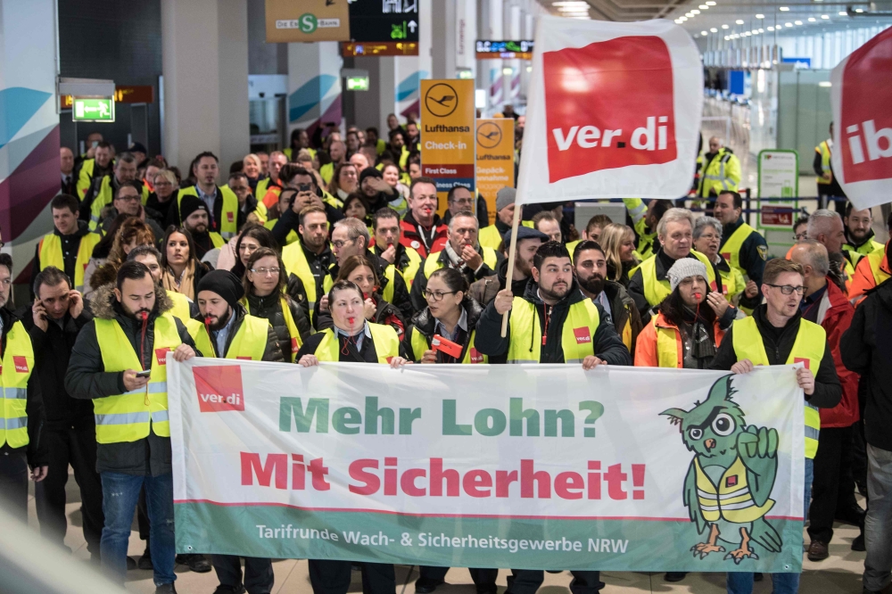 Members of Germany's Verdi union hold a banner reading 