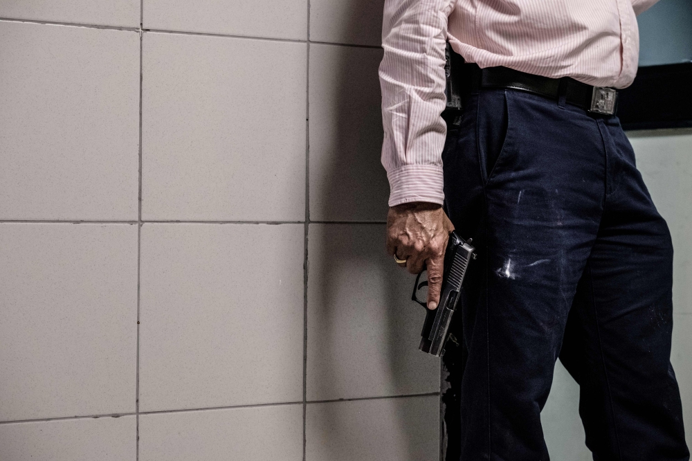 A security officer holds a gun in the building attached to the DusitD2 compound in Nairobi, on January 15, 2019, after a blast followed by a gun battle rocked the upmarket hotel complex.  AFP / Kabir Dhanji 
