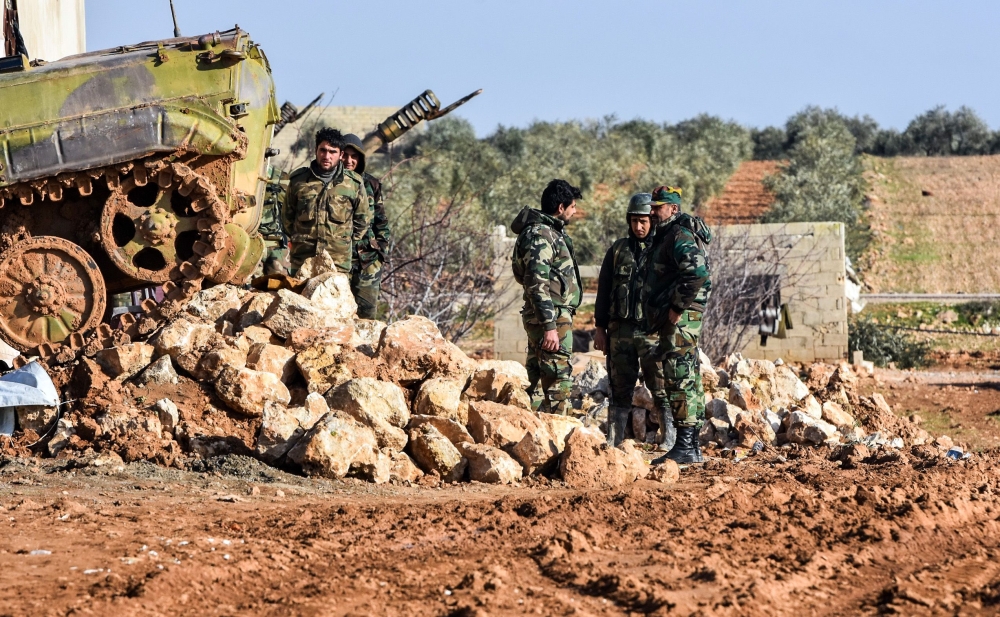 Syrian soldiers stand next to a deployed infantry-fighting vehicle at a government forces' position in the village of Hawshariya, northeast of the northern town of Manbij, on January 12, 2019. / AFP / George OURFALIAN