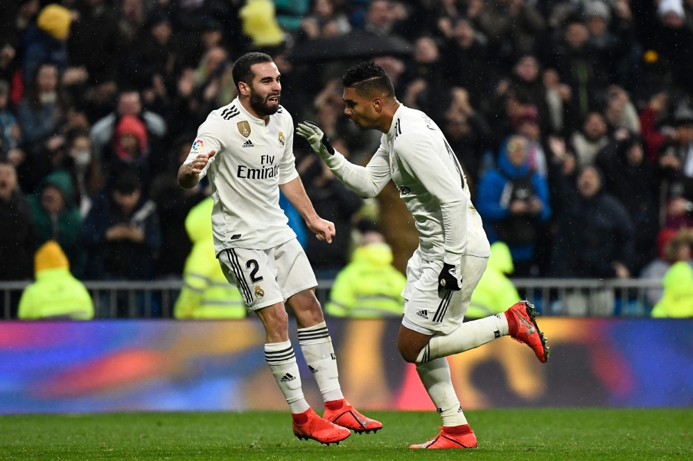 Real Madrid's Brazilian midfielder Casemiro (R) celebrates with Real Madrid's Spanish defender Dani Carvajal after scoring a goal during the Spanish League football match between Real Madrid and Sevilla at the Santiago Bernabeu stadium in Madrid on Januar