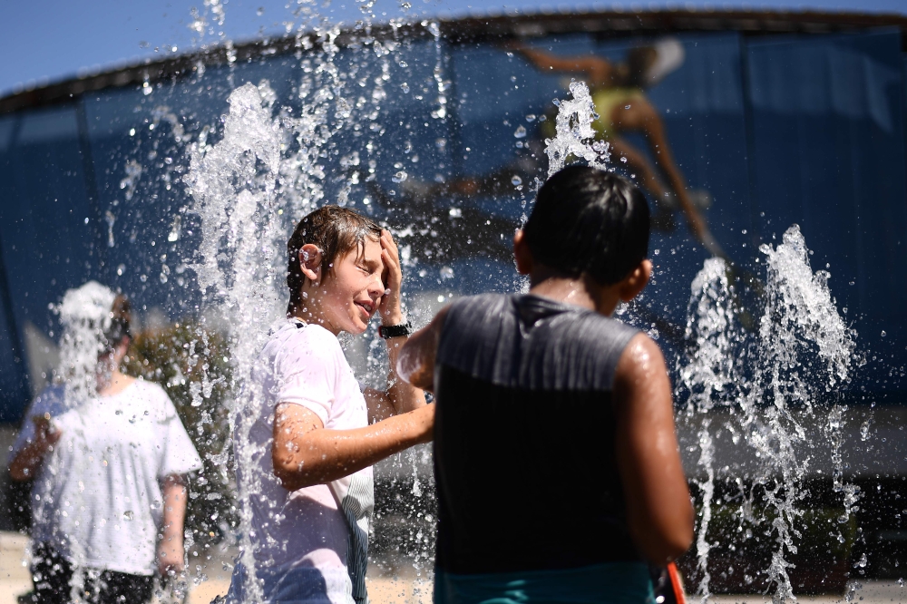 Children play in a fountain as they cool down from the heat on day 11 of the Australian Open tennis tournament in Melbourne on January 24, 2019. AFP / Jewel Samad 