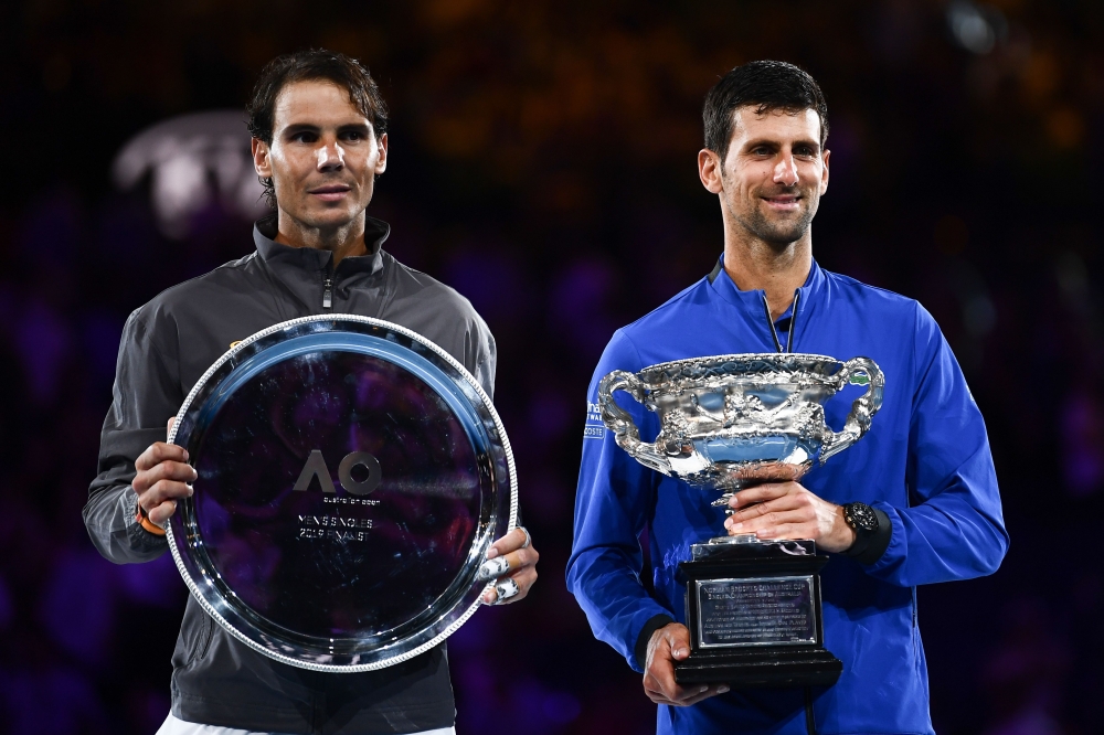 Serbia's Novak Djokovic (R) celebrates with the championship trophy during the presentation ceremony after his victory against Spain's Rafael Nadal (L) in the men's singles final on day 14 of the Australian Open tennis tournament in Melbourne on January 2