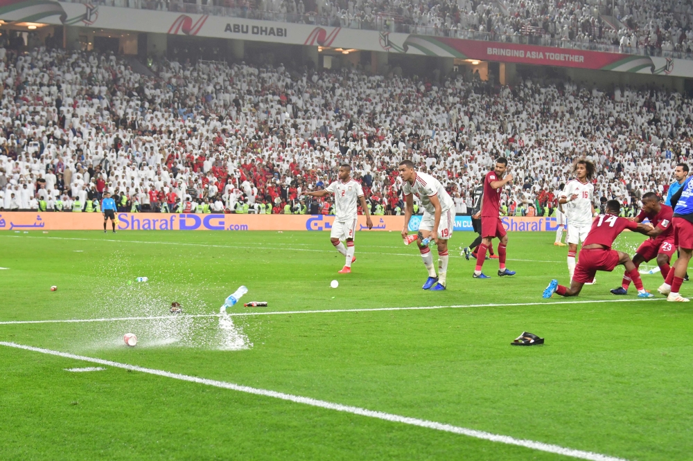 Fans throw bottles and flip-flops at the pitch during the 2019 AFC Asian Cup semi-final football match between Qatar and UAE at the Mohammed Bin Zayed Stadium in Abu Dhabi on January 29, 2019. / AFP / Giuseppe CACACE
