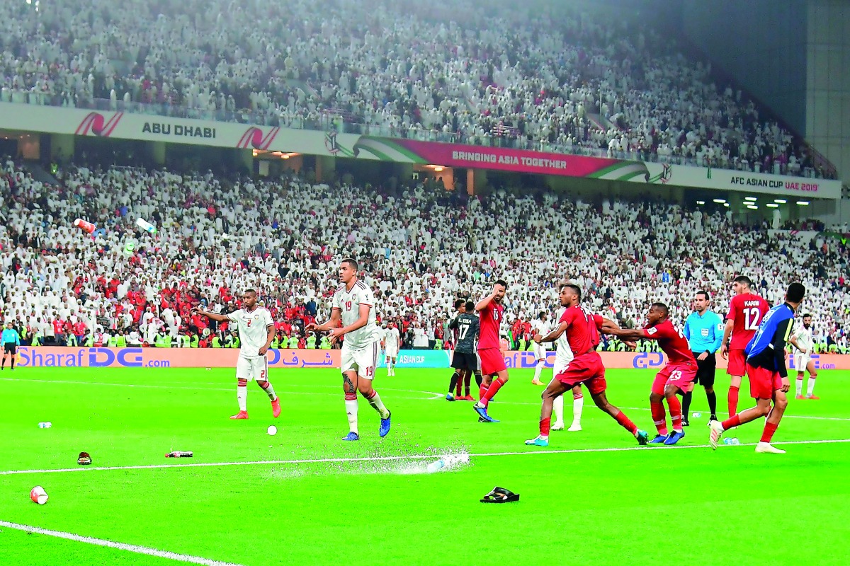 Fans throw bottles and flip-flops at the pitch as players take evasive action during the AFC Asian Cup semi-final at the Mohammed Bin Zayed Stadium, yesterday.