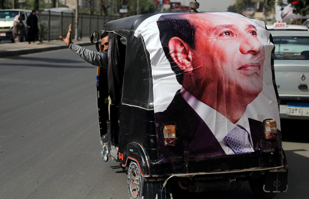 A man gestures as he rides a motorized vehicle showing a poster of Egyptian President Abdel Fattah al-Sisi in Cairo, March 27, 2018. Reuters/Ammar Awad