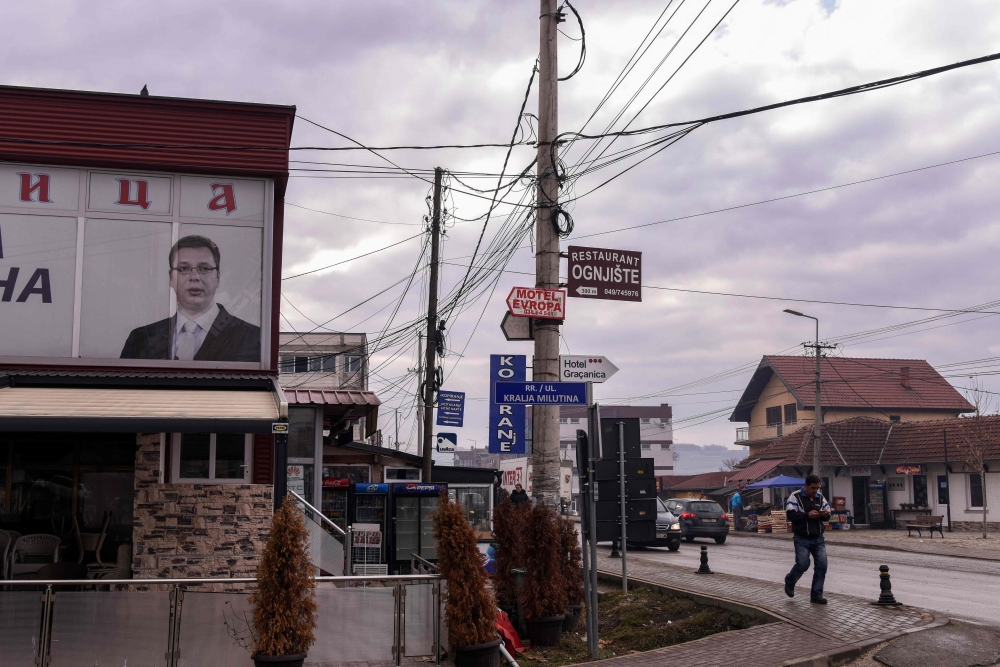 A man walks next to the portrait of the Serbian President displayed at the office of a Serbian political party in the town of Gracanica near Pristina on December 29, 2018. AFP/Armend Nimani
