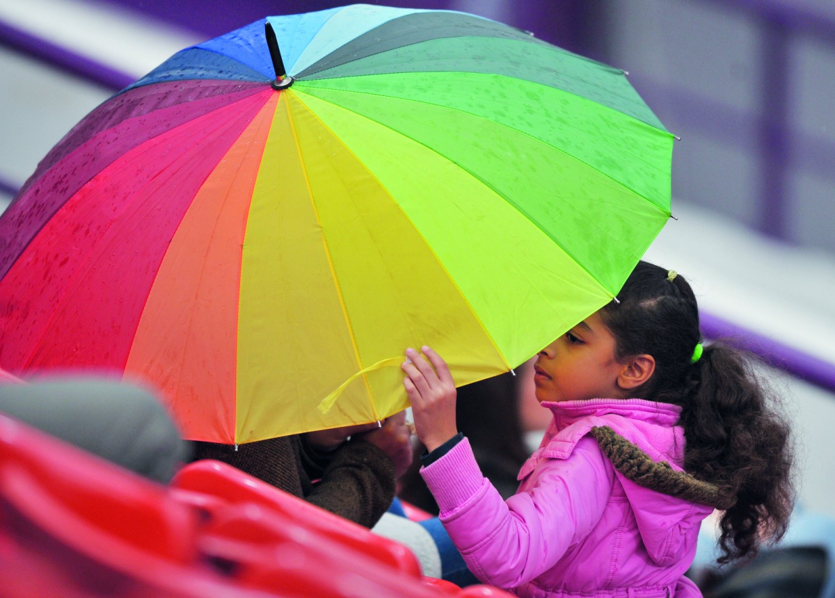 A young fan takes cover under an umbrella as rain stops play during the opening day of the Qatar Total Open 2019 at the Khalifa Tennis Complex yesterday. Pic: Baher Amin/ The Peninsula