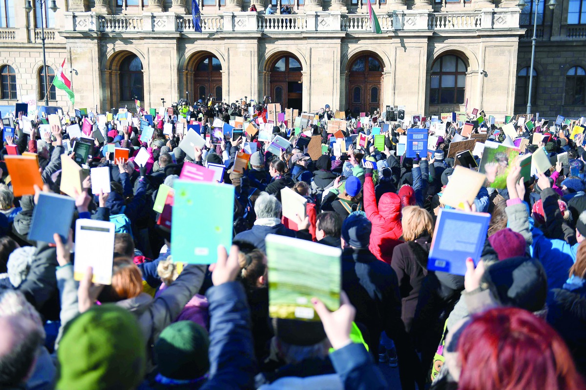 People hold up books as they protest against the education and scientific research policy of the Hungarian government in front of the Hungarian Academy of Sciences in Budapest on February 12, 2019. AFP / Attila Kisbenedek

