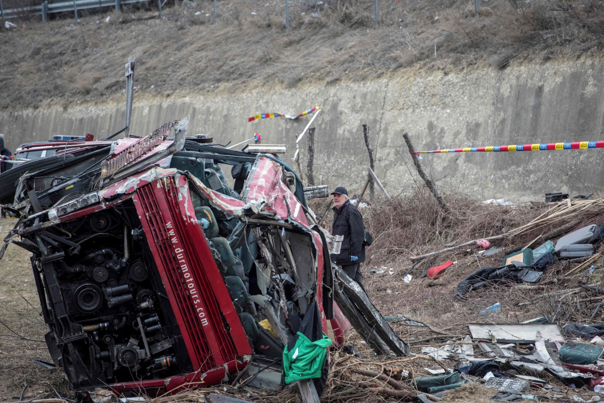 Police and investigators examine the wreckage of a bus at the crash site in the village of Laskarci, west of Skopje, on February 14, 2019.  AFP / Robert Atanasovski
