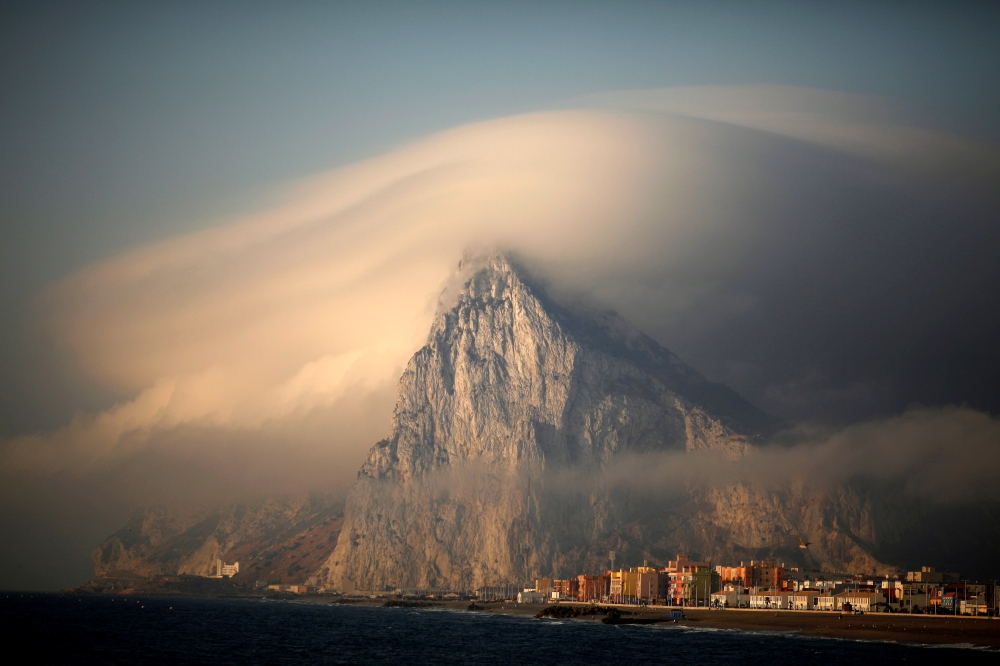 A cloud partially covers the tip of the Rock of the British territory of Gibraltar at sunrise from La Atunara port  in Algeciras bay, La Linea de la Concepcion in southern Spain August 18, 2013. Reuters/Jon Nazca