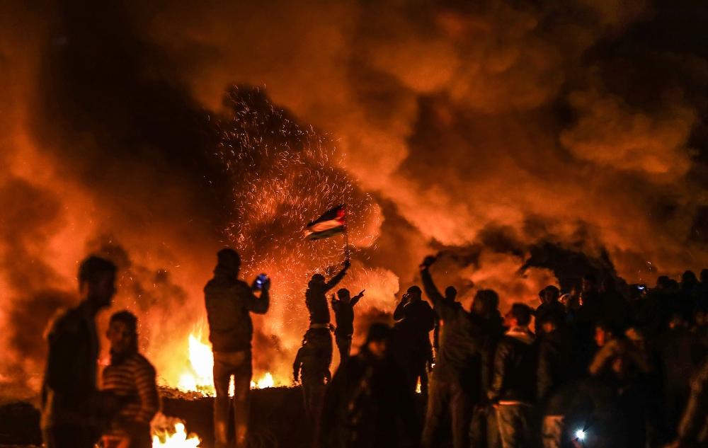 Palestinians burn torches and tires during the 