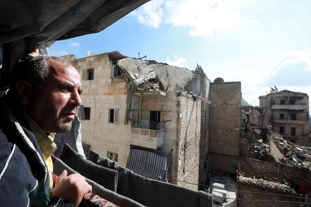 Syrian Izzat al-Dahan, 50, stands at the balcony of his family flat situated in a building heavily damaged during battles between rebel fighters and regime forces, in the former opposition held district of Salaheddin in the northern Syrian city of Aleppo 