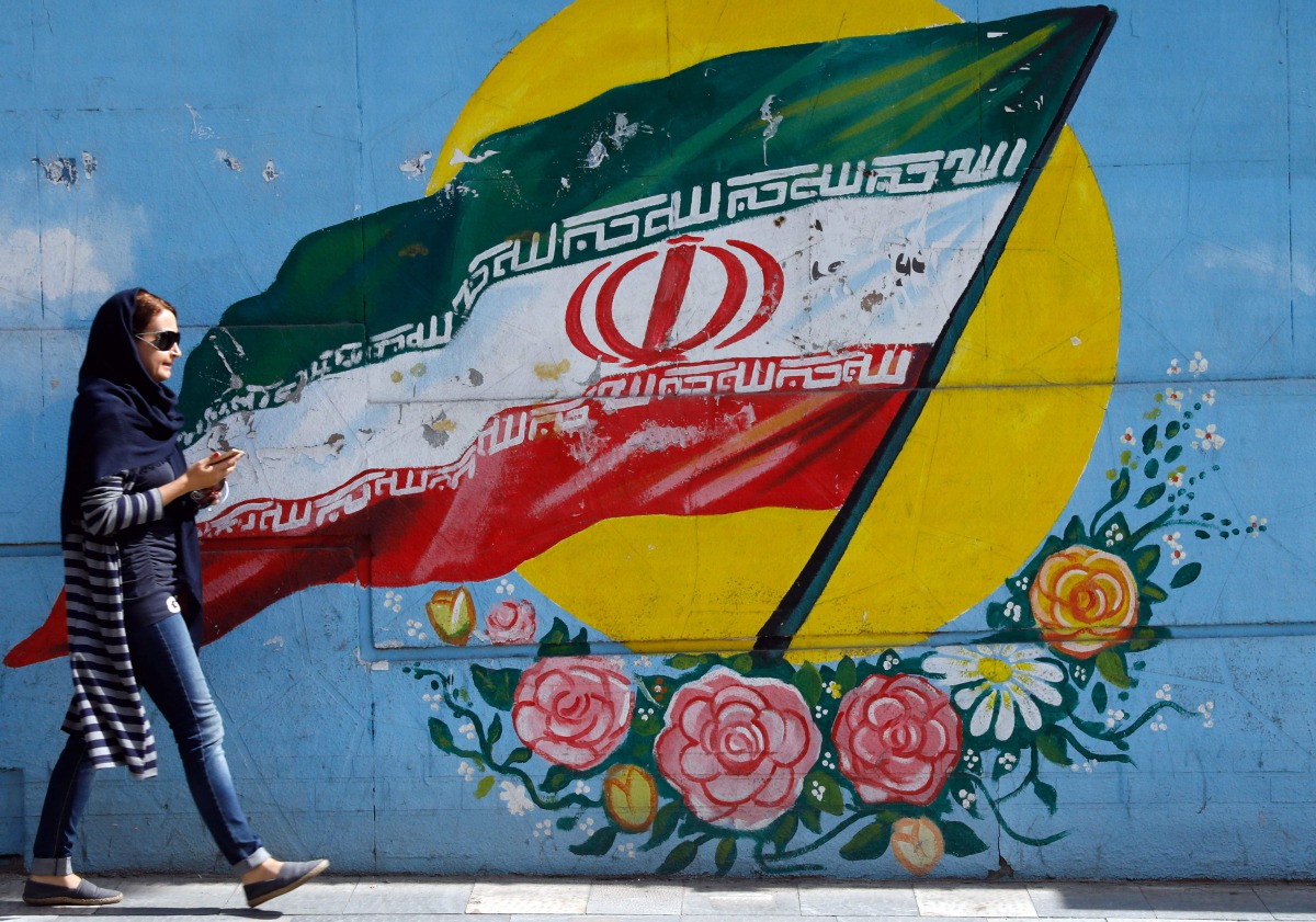 An Iranian woman walks past a mural of the Iranian flag in the capital Tehran on October 14, 2017. (AFP) 