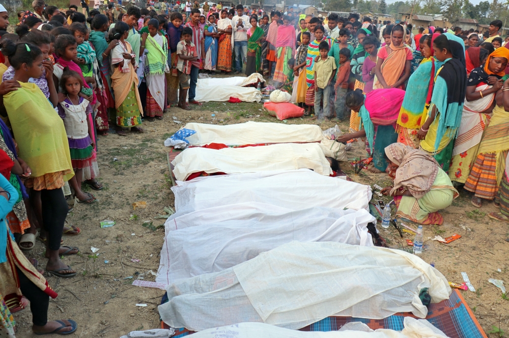 People stand next to the bodies of tea plantation workers, who died after consuming bootleg liquor, in Golaghat in the northeastern state of Assam, India, February 22, 2019. REUTERS/Stringer 