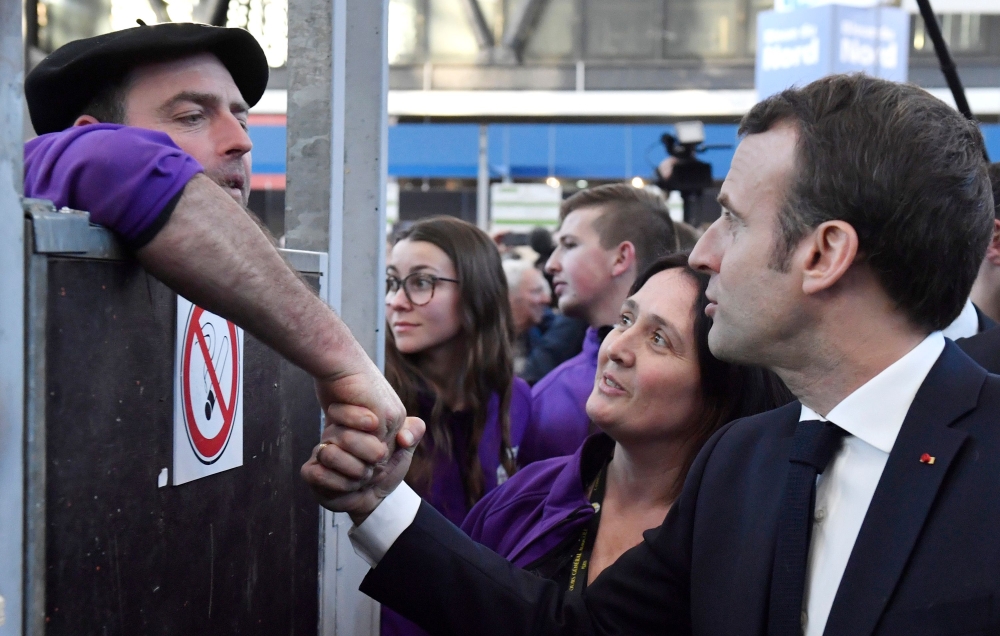 French President Emmanuel Macron (R) speaks with a farmer as he visits the 56th International Agriculture Fair (Salon de l'Agriculture) at the Porte de Versailles exhibition center in Paris February 23, 2019.  AFP / POOL / Julien DE ROSA