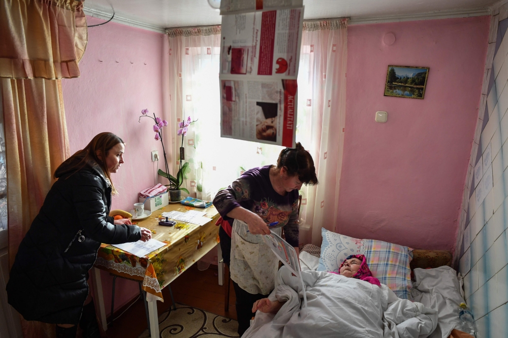 An elderly woman immobilised in bed is helped to vote by a relative in a mobile ballot box in Bardar village, on February 24, 2019, as Moldovans are called to the polls to elect new parliament members.  AFP / Daniel Mihailescu 