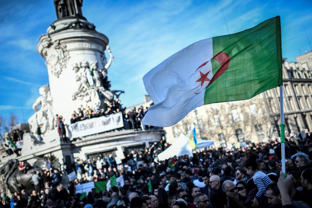 A protester holds up the Algerian flag during a rally against the Algerian president's bid for a fifth term in office on February 24, 2019 at the Place de la Republique in Paris.  AFP / STEPHANE DE SAKUTIN
