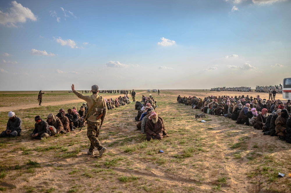 Men suspected of being Islamic State (IS) fighters wait to be searched by members of the Kurdish-led Syrian Democratic Forces (SDF) after leaving the IS group's last holdout of Baghouz, in Syria's northern Deir Ezzor province on February 22, 2019. / AFP /