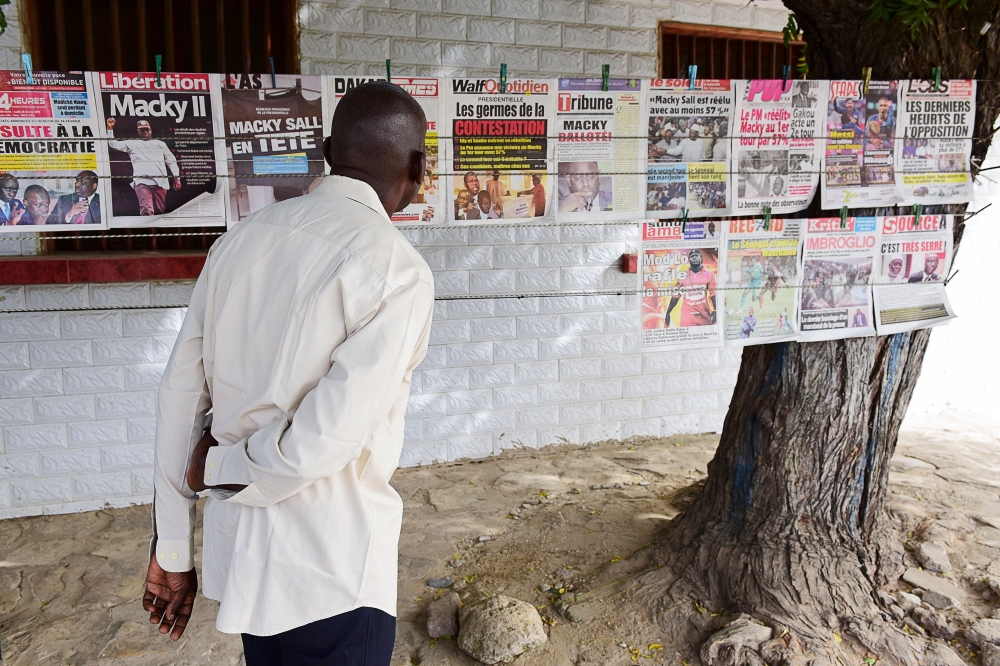 A man looks at newspaper front pages hung on a rope in Fann Hock neighbourhood, in Dakar, on February 25, 2019, one day after Senegal's presidential elections. AFP / SEYLLOU